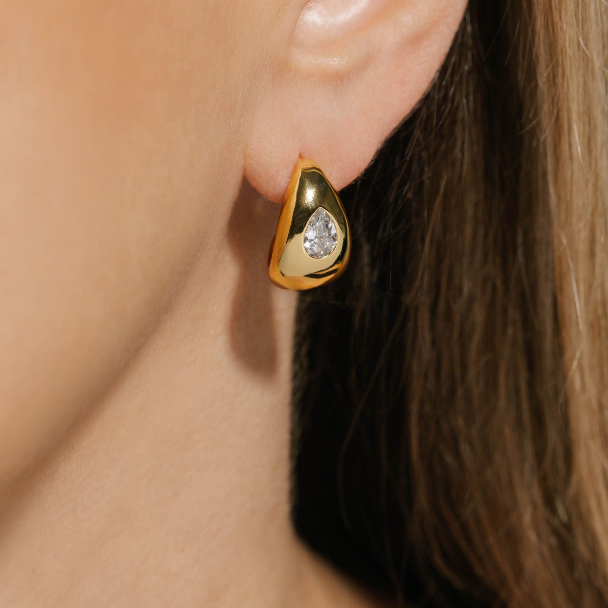 The Amadora Hoop | Crystal – modern gold-plated hoop with a pear-shaped crystal detail, worn on model for an elevated day-to-night look with a sculptural, high-shine finish, by The Perfect Hoop.
