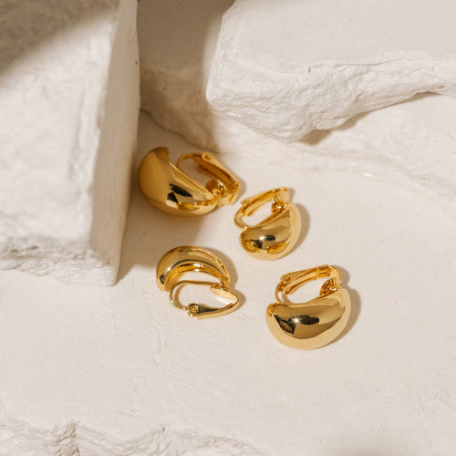 Gold Amadora Hoop Duo Clip-On earrings featuring a smooth, polished finish and a bold, curved design, displayed on a textured stone background. Elegant and versatile, these clip-on hoops by The Perfect Hoop offer a classic yet modern style