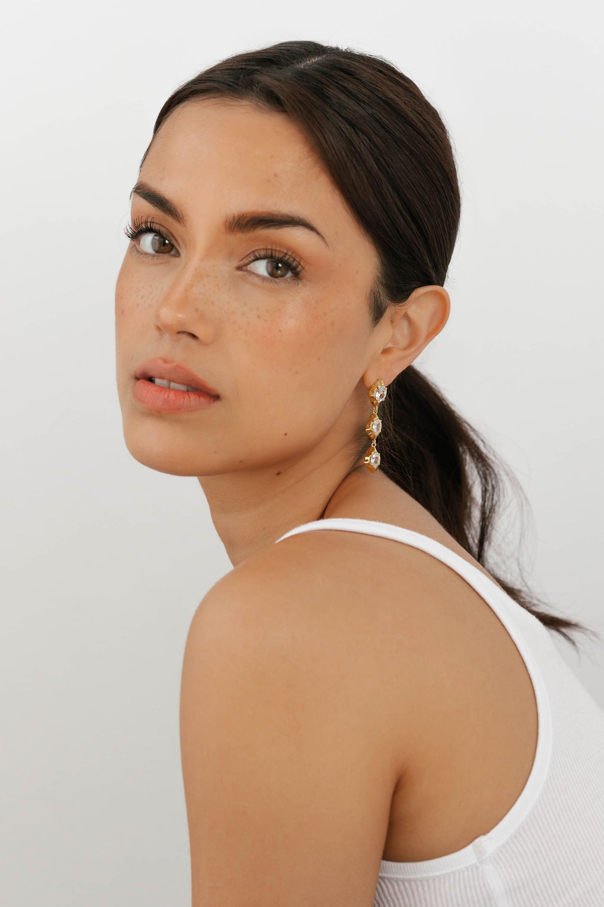 The Perfect Hoop Aura Drop Hoop in gold, featuring double teardrop crystal design on a warm-toned gold frame, worn elegantly on model.