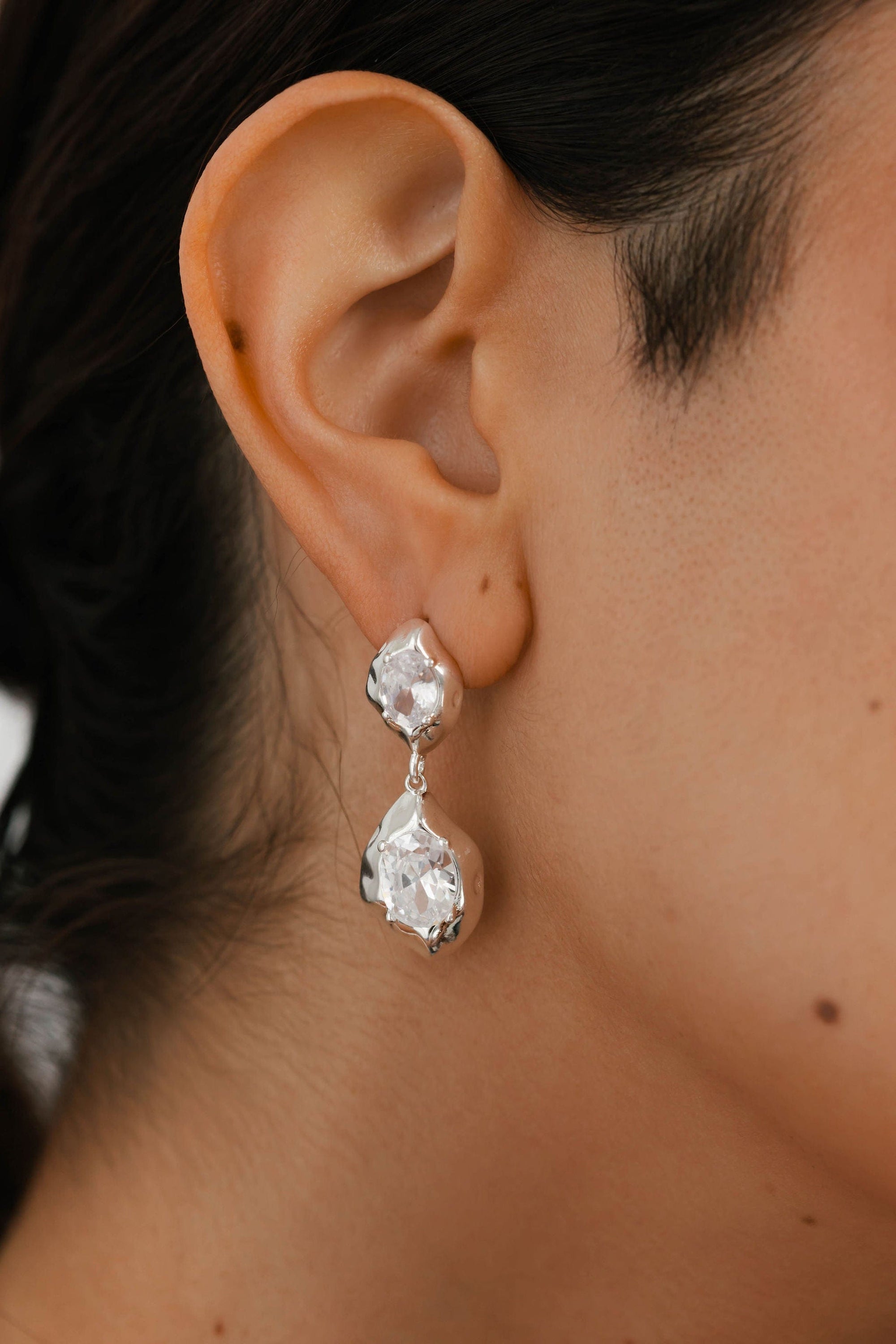 The Aura Hoop by The Perfect Hoop in sterling silver, worn with hair in low ponytail, emphasizing the crescent curve and gleaming surface.