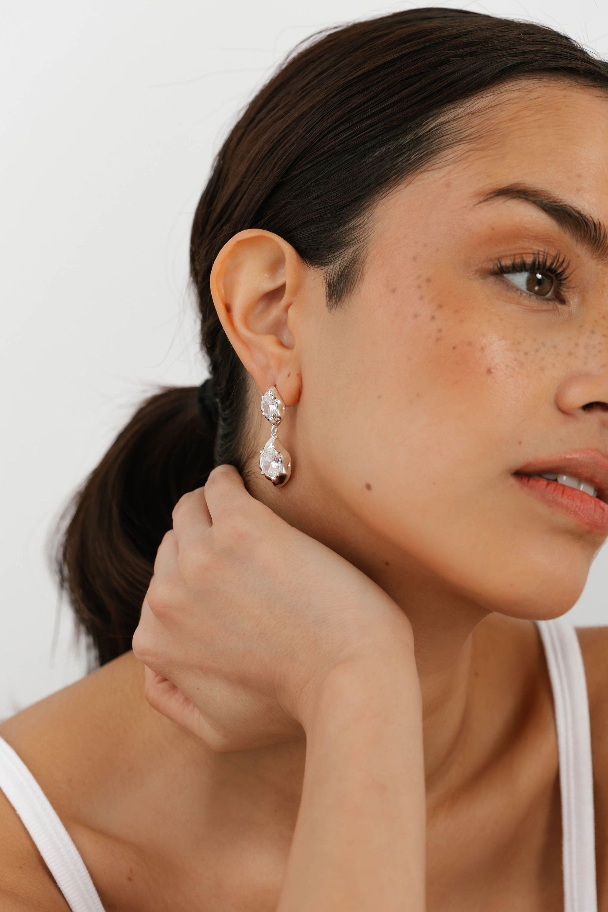The Perfect Hoop close-up of The Aura Hoop in silver, styled with neutral tones, featuring a softly domed crescent hoop with a reflective polished finish.