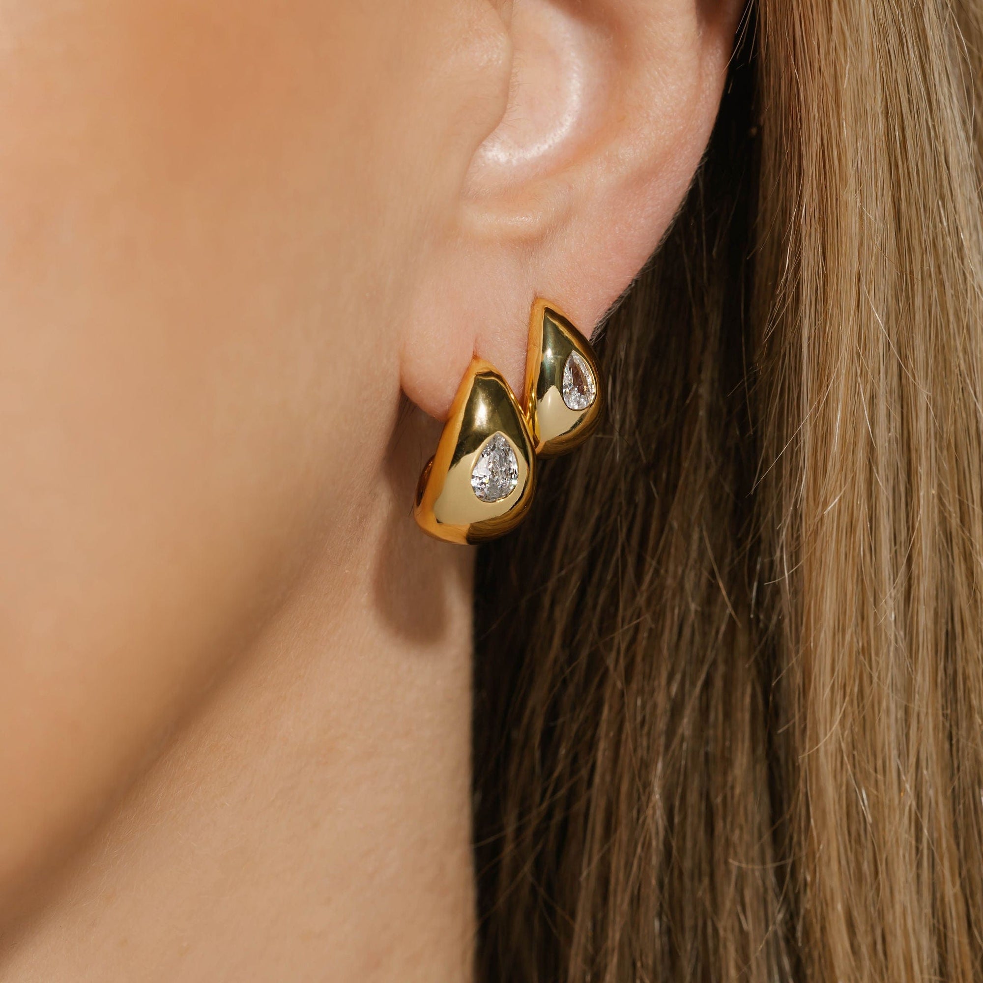 The Amadora Hoop Duo | Crystal – stacked 18K gold-plated sculptural hoops featuring pear-shaped crystal accents, worn on model for a bold and brilliant layered ear look, by The Perfect Hoop.